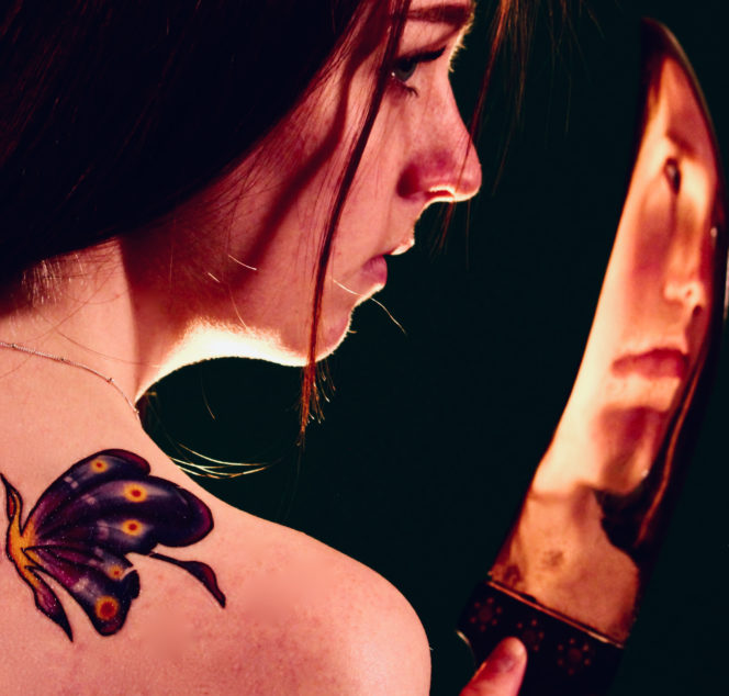 Lisa in profile looking at an image of her face distorted in the curve of a knife