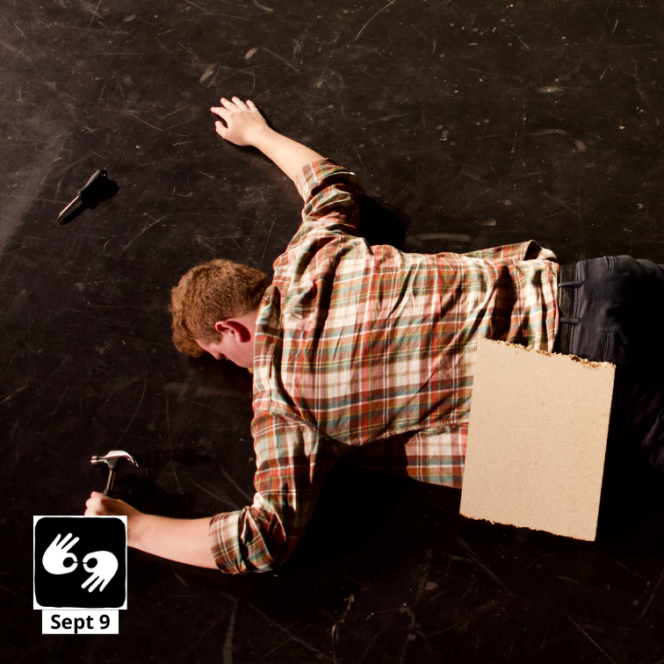 The actor lies face-down on a dark floor, clutching a hammer, with a broken piece of headboard resting on his back.