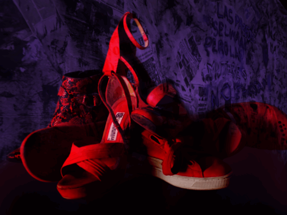 A pile of red women’s shoes bathed in dramatic light, set against a background of newspapers and the phrase 'Walls can be cleaned, but women don’t come back.