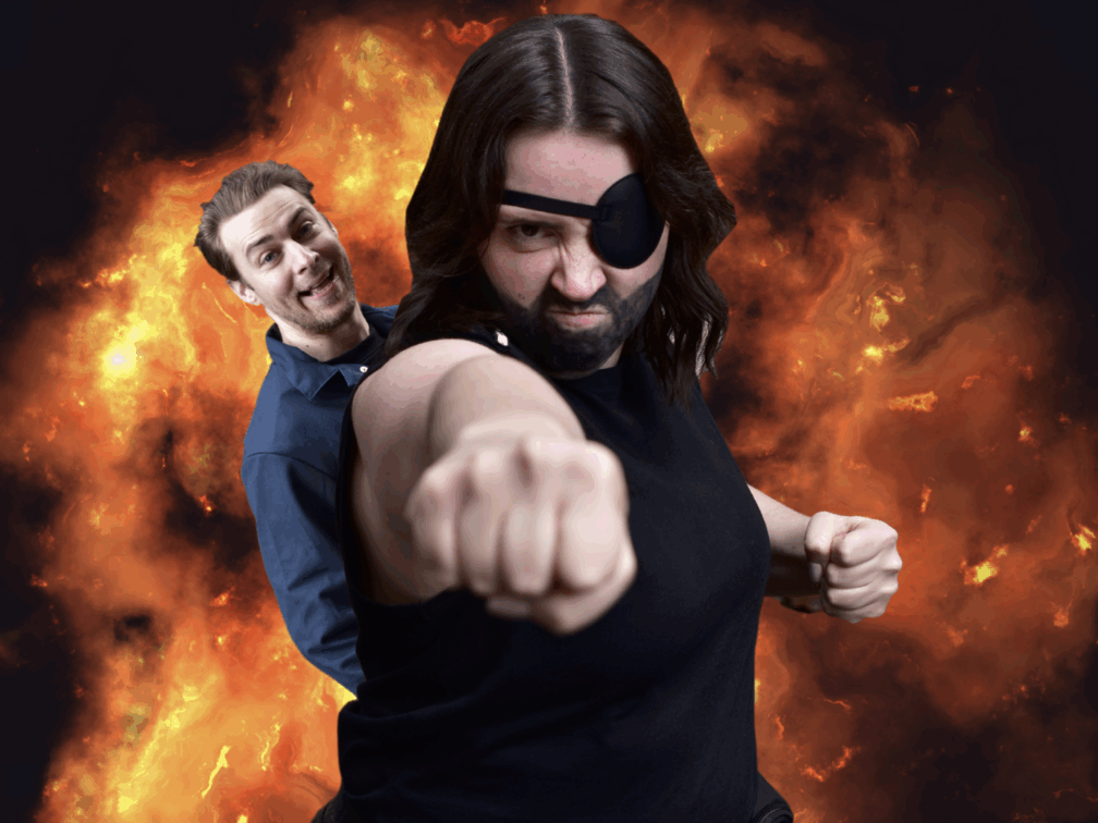 Tamlynn stands in front of an explosion, wearing a black eyepatch and a drawn-on beard. They are punching towards the camera and making a "tough" face. Popping up over their right shoulder is Rod with a big open-mouth smile.